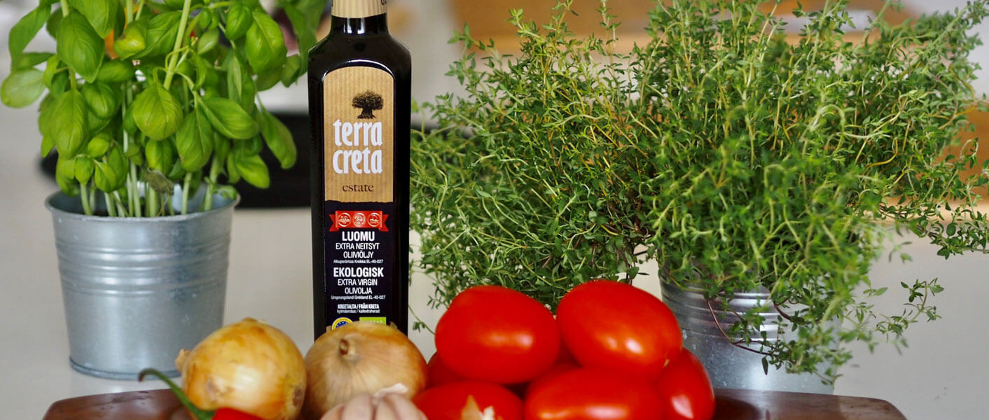 Pöydällä tomaattisen soffritton aineksia; Terra Creta oliiviöljy, tomaatit, basilika sekä sipulit.